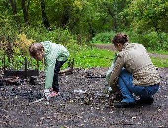 two-females-in-the-woods-picking-up-trash
